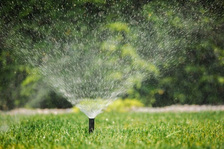 A sprinkler spraying grass by Thrive Landscape Services
