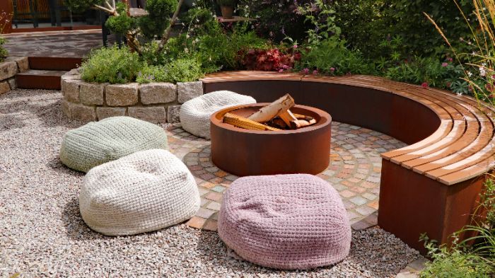 Cobblestones around a firepit by a bench and beanbag chairs by Thrive Landscape Services