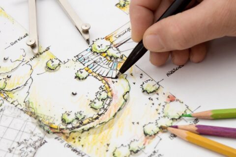 Someone drawing a blueprint of a landscape design by Thrive Landscape Services