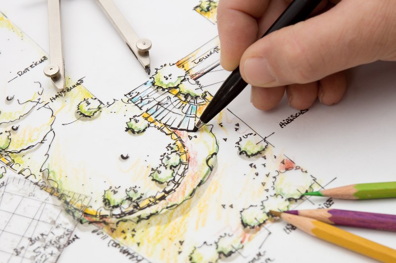 Someone drawing a blueprint of a landscape design by Thrive Landscape Services